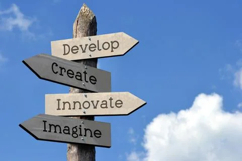 Develop, create, innovate, imagine - wooden signpost with four arrows Stockfoto's