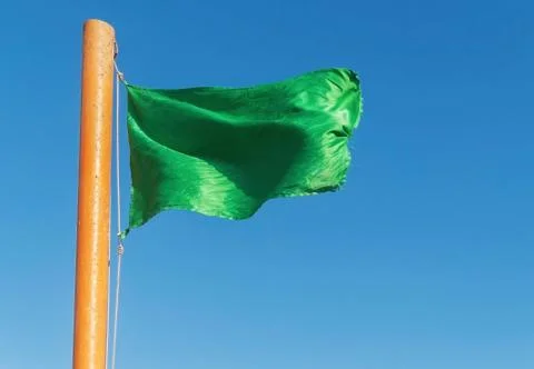 Develop green flag on a background of blue sky 스톡 사진