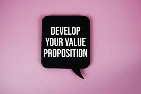 Develop Your Value Proposition text with speech bubble top view on pink bac.. Stock Photos