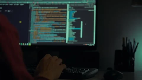 Developer coding at night with computer screen displaying programming code i Stock Footage 323764672
