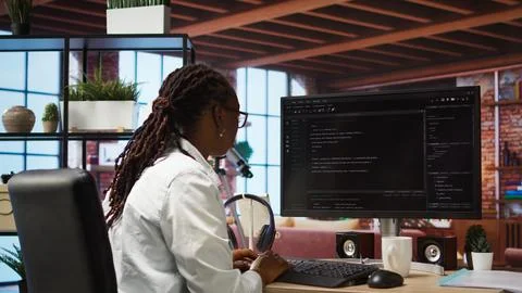 Developer at computer desk coding while listening music Stock-Fotos