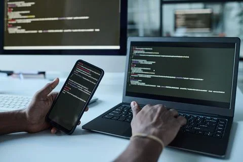 Developer connecting smartphone with codes to laptop Stockfoto's