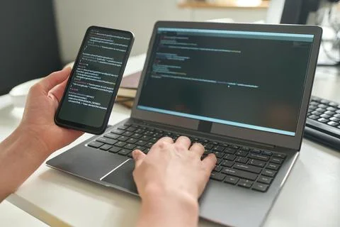 Developer connecting smartphone with laptop Foto stock