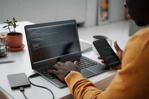Developer connecting smartphone with laptop to work with codes Stockfoto's