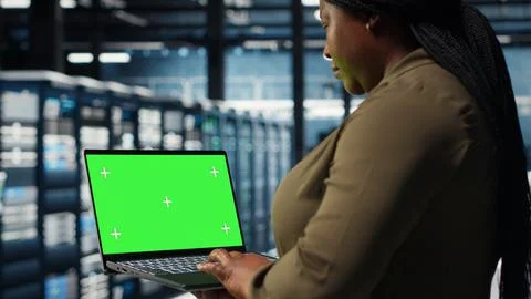 Developer in data center using green screen laptop to upgrade systems Stock Photos