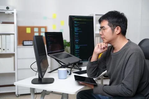 Developer Engaged in Coding and Problem Solving at a Workspace with Multiple 库存照片