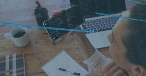 Developer examining code on smartphone by laptop on home office desk with code Stockfoto's