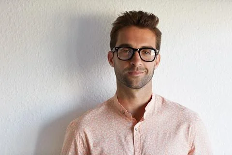 Developer, geek and happy man with glasses on a wall background for career .. Fotos Stock