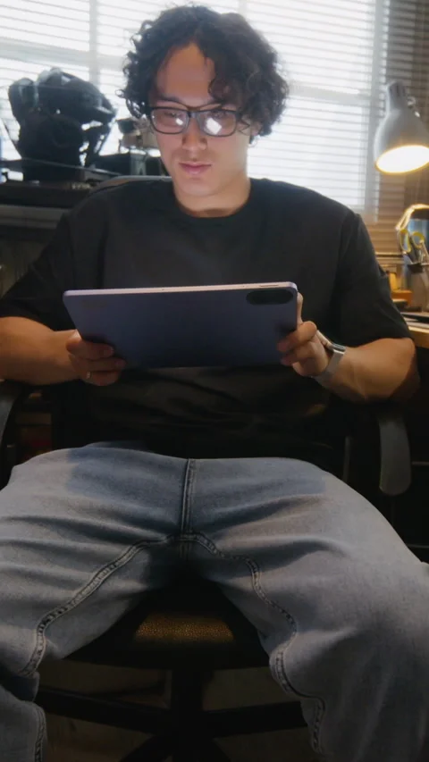 Developer with Glasses Using Tablet While Code Loading on Screen Stock Footage 338421695