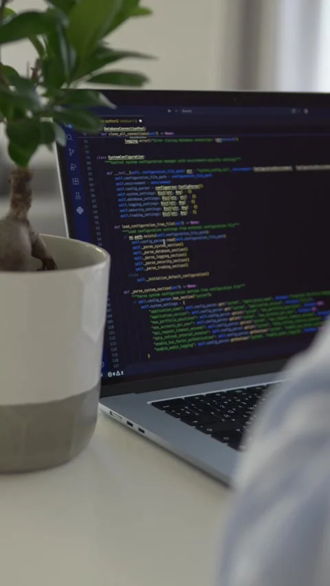 Developer holds glass and drinks water near laptop displaying source code. AI 스톡 동영상 345653618