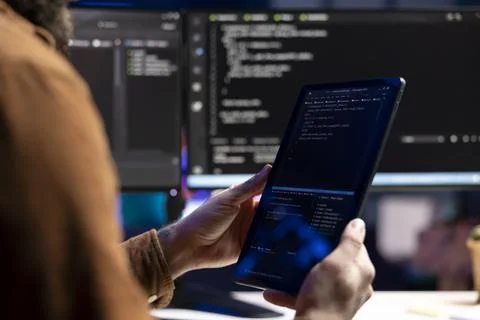 Developer inspecting coding on portable device, looking to fix potential issues Foto stock