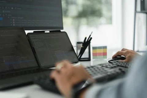 Developer programmer checking code on multiple monitor while programming to.. Stock Photos