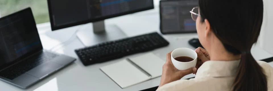 Developer programmer drinking coffee and checking code on monitor for progr.. Stockfoto's
