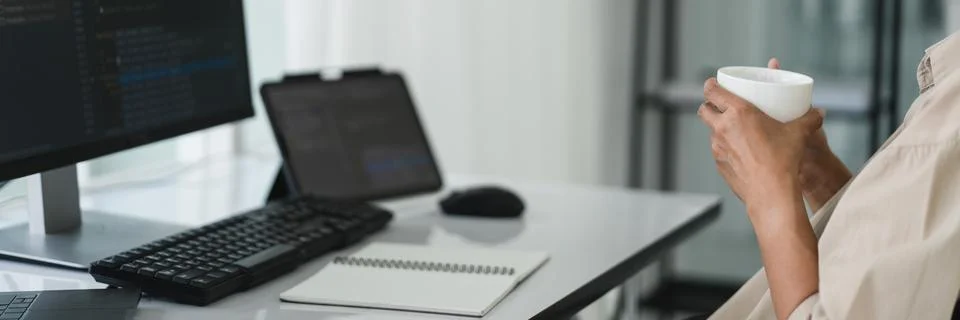 Developer programmer drinking coffee and checking code on monitor for progr.. 库存照片