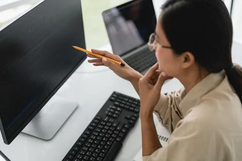 Developer programmer holds pencil and checking code on monitor while progra.. 写真素材