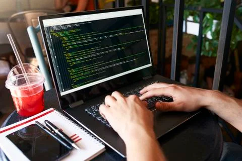 Developer programmer with laptop. Program code and script data on screen. Young Stock Photos