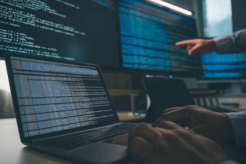 Developer programming code at a multi monitor workstation with laptop and s.. Foto stock