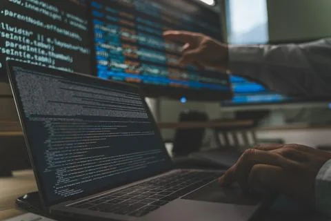 Developer programming code at a multi monitor workstation with laptop and s.. 스톡 사진