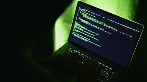 Developer sits at laptop with green backlight, typing computer code on keyboard Stock Footage 317940531