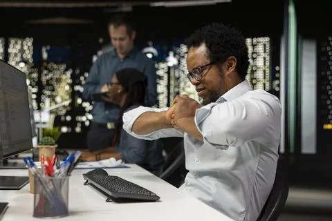 Developer stretching limbs at PC desk in office 写真素材