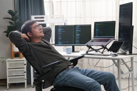 Developer Taking a Break from Coding at a Workspace with Multiple Computer Stock Photos