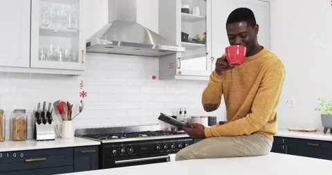 Developer tapping tablet while sipping mug in kitchen reading code causing Stock Footage 319678699