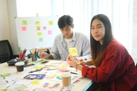 Developer team working on app wireframes at desk with sticky notes and digital Stock Photos