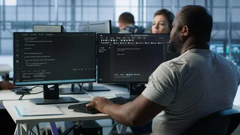 Developer typing code on PC to mend data center racks Stock Photos