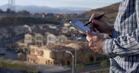 Developer using tablet computer in front of new construction 4K Stock Footage 84130135