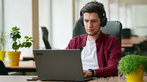 Developer, video editor man in headphones working with laptop at spacious Stock Footage 219694168