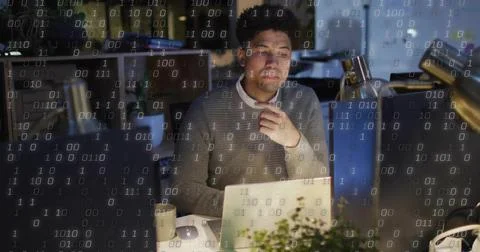 Developer wearing grey sweater analyzing binary code in office at night, with 写真素材