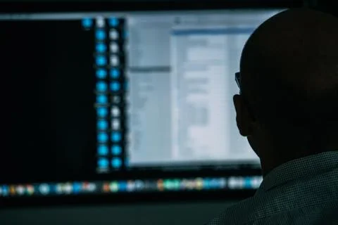 Developer, working behind the desk, analysing diagram on the monitor 写真素材