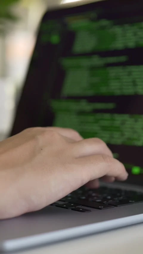 Developer works on laptop displaying colorful green source code in modern Stock Footage 345654409