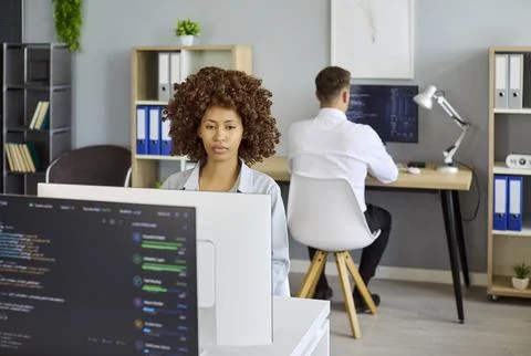 Developers coding software in modern office with monitors and team collaboration Stock-Fotos