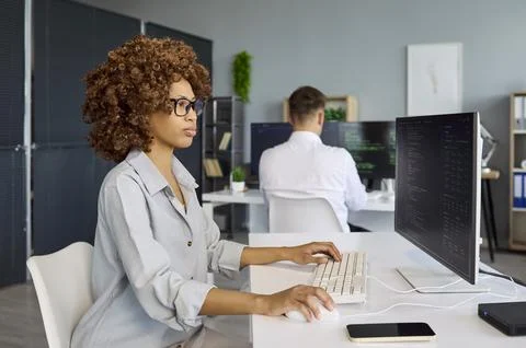 Developers coding software at modern office with monitors and teamwork focus Stock Photos