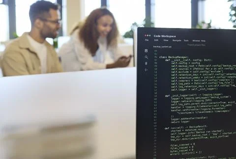Developers collaborate in office with code on computer monitor and blurred Stock-Fotos
