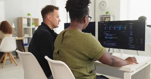 Developers collaborating on code review at computers in modern office workspace Video stock 336490546
