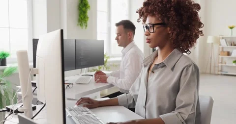 Developers collaborating at computers in modern office, coding software together Stock Footage 340532686