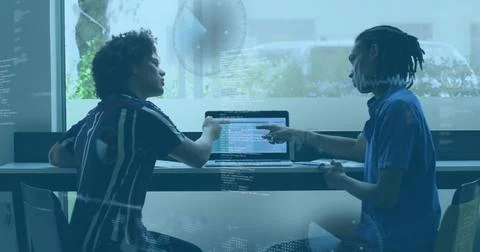 Developers collaborating on laptop typing code in meeting room, with glass Stock Photos