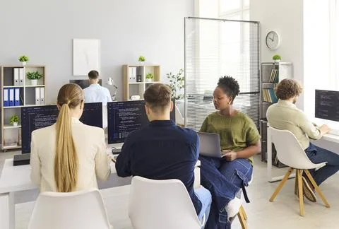 Developers collaborating in modern office, coding software on computers together Stock Photos