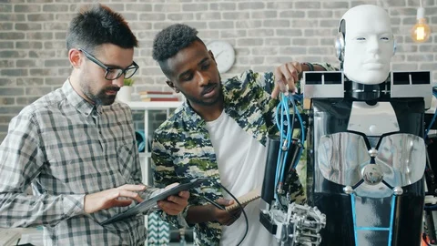 Developers constructing and testing robot in office using tablet indoors Stock Footage 119575882