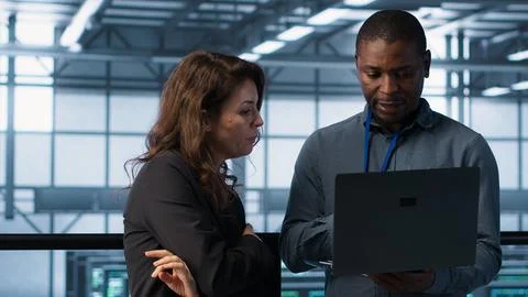 Developers in data center workspace coding on laptop, analyzing metrics Stock Photos