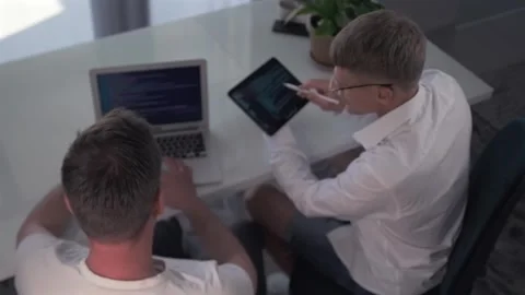 Developers fix bugs on a tablet and laptop. Stock Footage 294298737