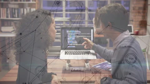 Developers pointing at laptop showing code at desk while network diagrams fading Stock Footage 313307722