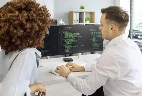 Developers Reviewing Code on Dual Monitors in Office, Team Collaboration Session Stock Photos
