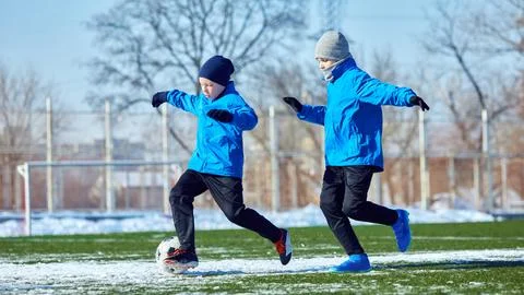 Developing ball control. Boys in blue jackets practicing dribbling on outdoor Stock Photos