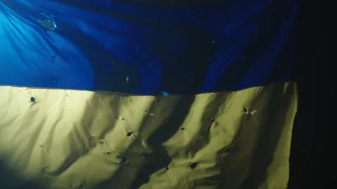 The developing blue yellow flag of Ukraine on a black background illuminated by Stock Photos