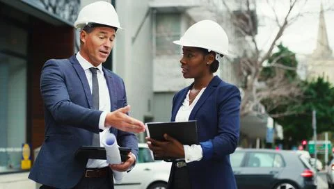 Developing the city for the better together. Shot of two businesspeople weari Stock Photos