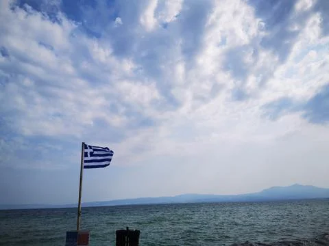The developing flag of Greece on the background of the Mediterranean Sea. Stockfoto's