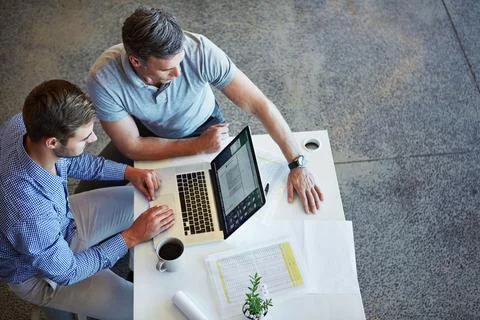 Developing a killer strategy. two colleagues using a laptop in a meeting at the Stock Photos
